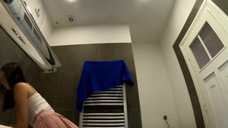 زن برنزه بدون سینه‌بند پاهای زیبا و باسن خیره‌کننده‌اش را در مینی صورتی حمام نمایش می‌دهد