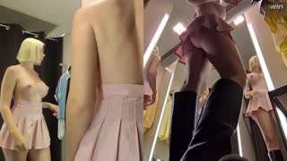 In a bustling dressing room, a hidden camera captures an upskirt view of a blonde amateur's juicy pussy as she tries on clothes