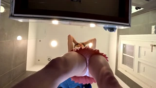 Brune sans soutien-gorge exhibe ses jambes sublimes et son cul en jupe mini rose dans la salle de bain
