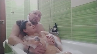 The couple relaxes in the bath with her big boobs and ass on display